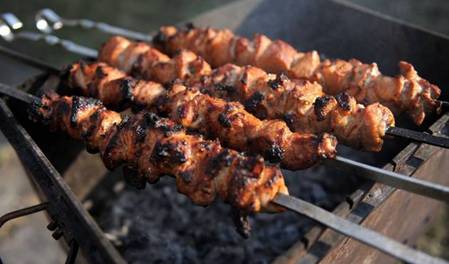 Grilling marinated shashlik preparing on a barbecue grill over charcoal.  Shashlik is a form of Shish kebab popular in Eastern Europe. Shashlyk (meaning  skewered meat) was originally made of lamb. Stock Photo